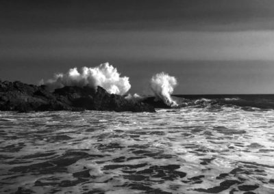 black and white wave hitting rocks
